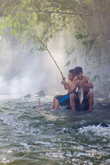 Two Asian boys fishing in the river, the happiness of children in the countryside.