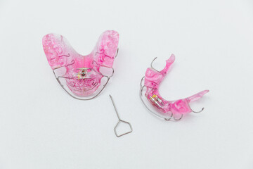 Set of pink removable orthodontic appliances for upper and lower jaw with expansion screw key, pediatric dentistry and professional bite correction concept