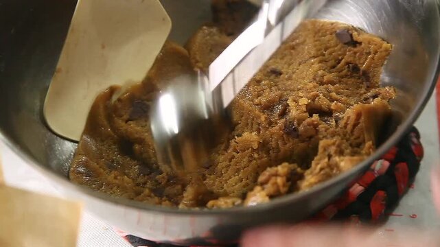 Scooping raw chocolate chips cookies being prepared for baking
