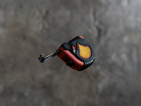 The mechanic throws the measuring tape out of his hand and it goes into free fall.