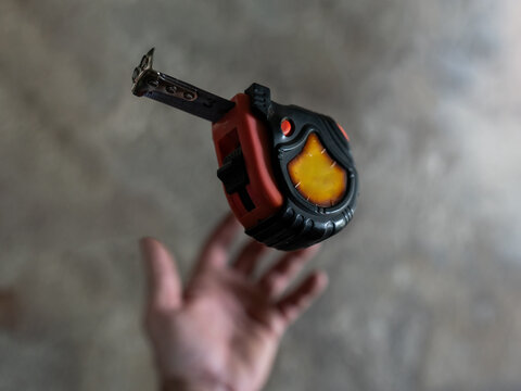 The mechanic throws the measuring tape out of his hand and it goes into free fall.