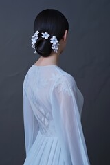 Minimal female back portrait with floral hair detail on dark background.