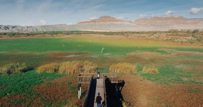 Aerial view of Nallihan Bird Sanctuary in Ankara, Turkey. Colorful rocky mountains, wetlands and a wooden pier with people enjoying the scenic landscape at sunset.