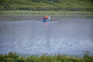 ishermen floats on the lake in the boat and fishing. Morning with fog over water.