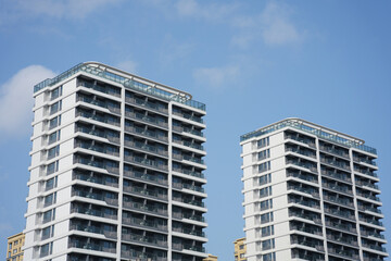 Fototapeta premium Two modern high-rise residential buildings against a clear blue sky background