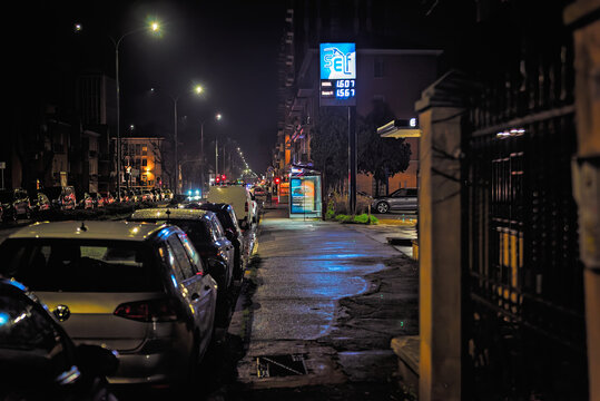 Strada urbana di notte con stazione di servizio illuminata e traffico cittadino