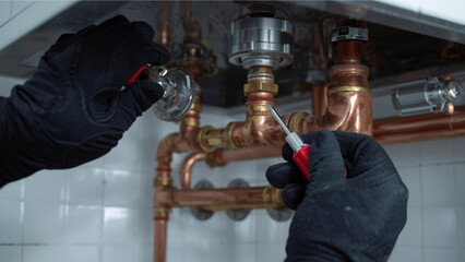 Plumber Working on Copper Pipe System with Screwdriver