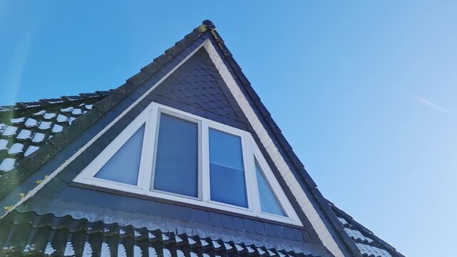 Melting snow on a house roof under clear blue sky