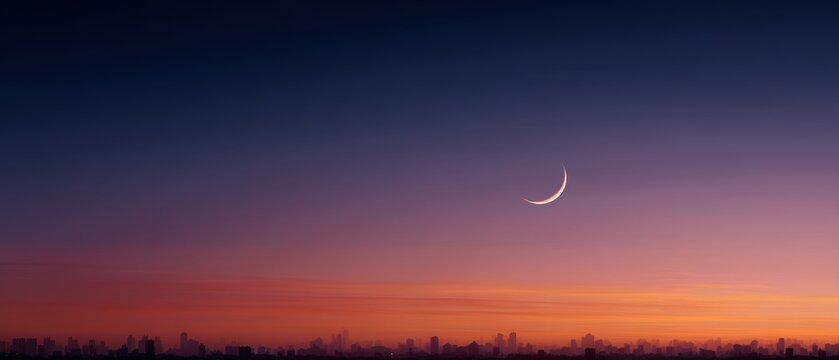 Crescent moon with dramatic sunset sky and city silhouette, ramadan banner