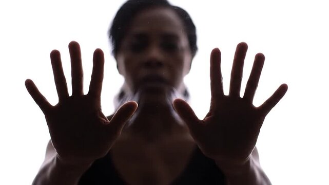 Silhouette of person with hands pressed against a barrier symbol of stop boundary refusal protection