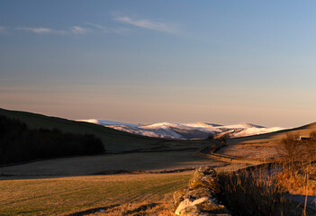 Galashiels, Scotland - February 14, 2026: Snow-covered hills rise above a winding road in the countryside