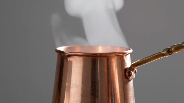 Close-up of a copper pot with steam rising, suggesting hot liquid or cooking.