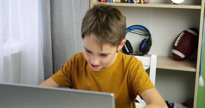 Upset boy reacts after losing computer game. Child hits table with hand in frustration. Emotional gamer shows anger and stress. Concept of disappointment, digital failure, and childhood reaction.