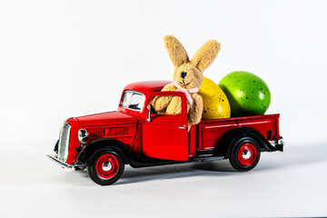 red classic toy pickup truck with Easter bunny and colored Easter eggs on white background