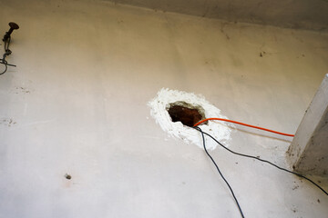 exposed hole in wall with electrical wires extending through © Tohamina