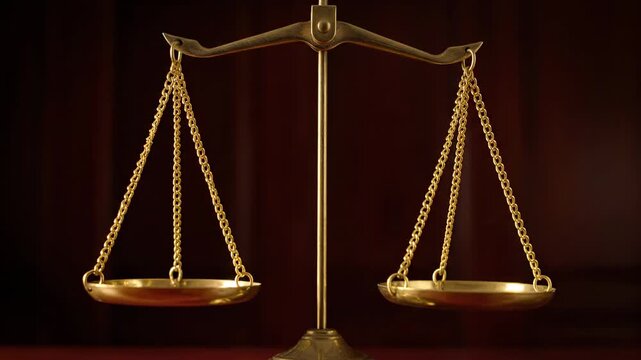 A close-up view of a golden balance scale against a dark, warm backdrop