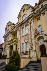 Fototapeta premium Historic yellow townhouse facade with columns and ivy