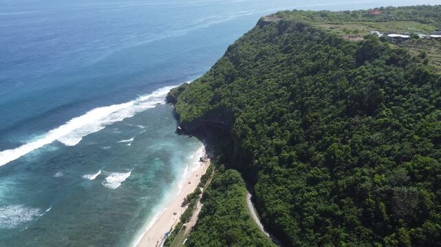 Aerial drone standstill hover above coastline towards beach entrance and cliffs at Nyang Nyang Beach, Bali Indonesia