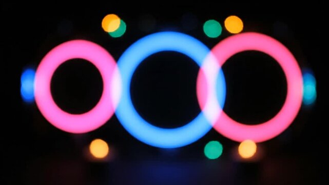 Abstract colorful interlocking rings with bokeh on dark background