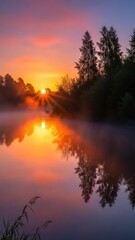 Fototapeta premium Serene sunset over a misty lake with silhouettes of trees reflected in still water.