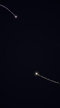 Long exposure shot of two glowing trails of sparks flying through a dark background