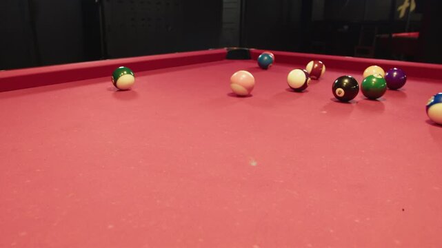 Close up of chalked cue and white ball on a red felt table. Playing pool during club night. Scene of billiard game and professional strike of scattered balls on surface near pocket. No face