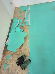 Removing the old, porous impact sound insulation that was under a laminate floor. Interior renovation. Work gloves.