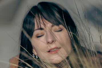 Caucasian young female relaxing outdoors with eyes closed amidst tall grasses