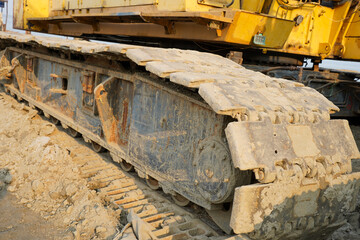 closeup of heavy construction machinery crawler track covered in dirt and mud