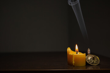 Blue texture smoke from incense aroma stick in vintage holder motion rising above in holiday stands near burning wax candle fire on copy space dark background. Meditation, relaxation concept © Anastasia.photoyoga