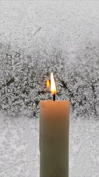 A candle burns against the background of a frozen window №2