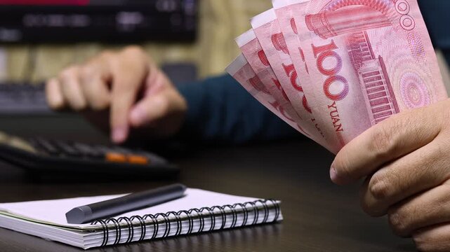 Close up view of man hands, calculator, Chinese Yuan (CNY) banknotes. Concept of saving money for retirement, cash settlement, financial goals, success, literacy and income planning in China.