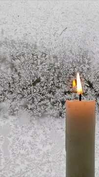 A candle burns against the background of a frozen window №3