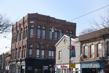 Fototapeta premium looking west on Queen St E to building facades and signs of Dirty Pawz Self-Serve Dog Wash, Tim Hortons, and historic Poulton Block, Toronto