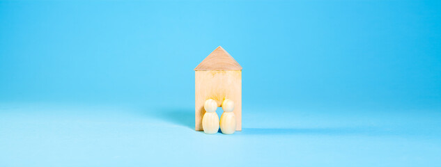 wooden house model with two wooden blocks on blue background