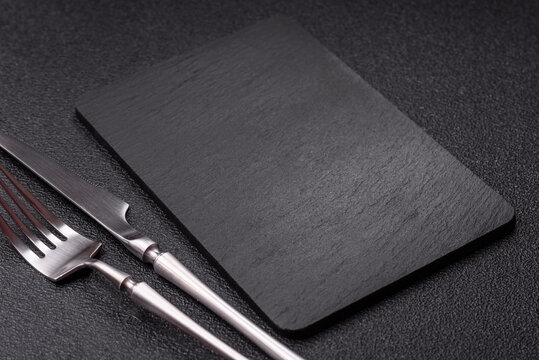 An empty slate cutting board with cutlery on a kitchen counter. Slate cutting board
