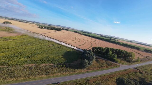Aerial 180-degree panorama rotating left over agricultural fields and distant hills, rural landscape, 4K 