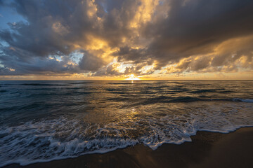 Fototapeta premium Golden Sunrise Over Atlantic Ocean with Dramatic Clouds and Waves