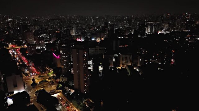 Night aerial view pulling back from avenue with heavy traffic in Sao Paulo, Brazil. Drone shot revealing Viaduto Julio de Mesquita Filho highway and cityscape