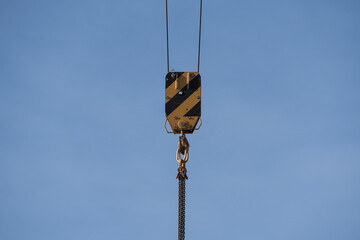 Fototapeta premium Close up of construction crane hook and pulley block against clear blue sky, heavy lifting equipment and industrial safety concept