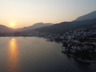 Fototapeta premium Coastal City at Sunset: Tranquil Waters and Mountain Backdrop Scenery