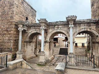 Obraz premium Ancient Roman triumphal arch with three arches and historical stone architecture in overcast weather