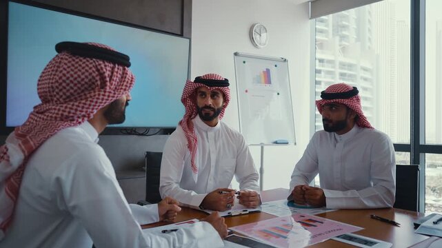 Arab businessmen wearing emirati kandura meeting in office for business deal - Corporate business group of middle-eastern people working in an international company in middle east 