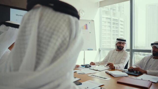 Arab businessmen wearing emirati kandura meeting in office for business deal - Corporate business group of middle-eastern people working in an international company in middle east 