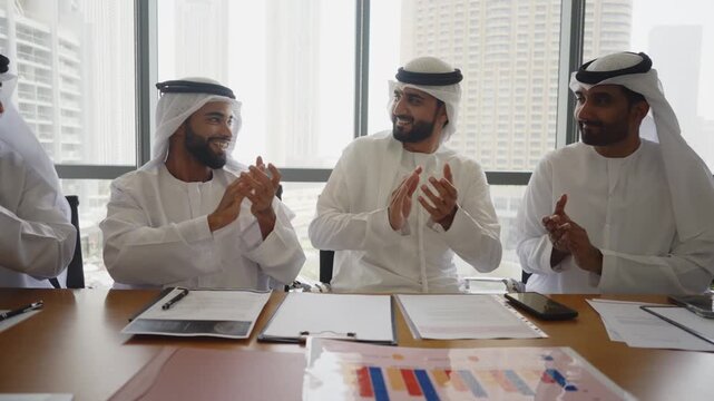 Group of corporate arab businessmen meeting in the office - Business people wearing traditional emirati kandura working together in Dubai	
