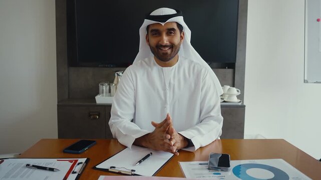 Handsome man with dish dasha working in his business office of Dubai. Portraits of a successful businessman in traditional emirates white dress. Concept about middle eastern cultures	