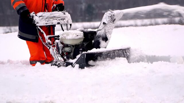 A man with a snow blower removes snow