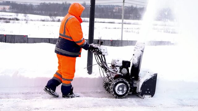 A man with a snow blower removes snow
