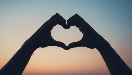 A pair of hands forming a heart shape against a sunset