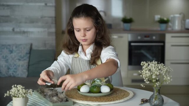 A girl decorating Easter eggs at home, preparing for a family holiday and a spring tradition
